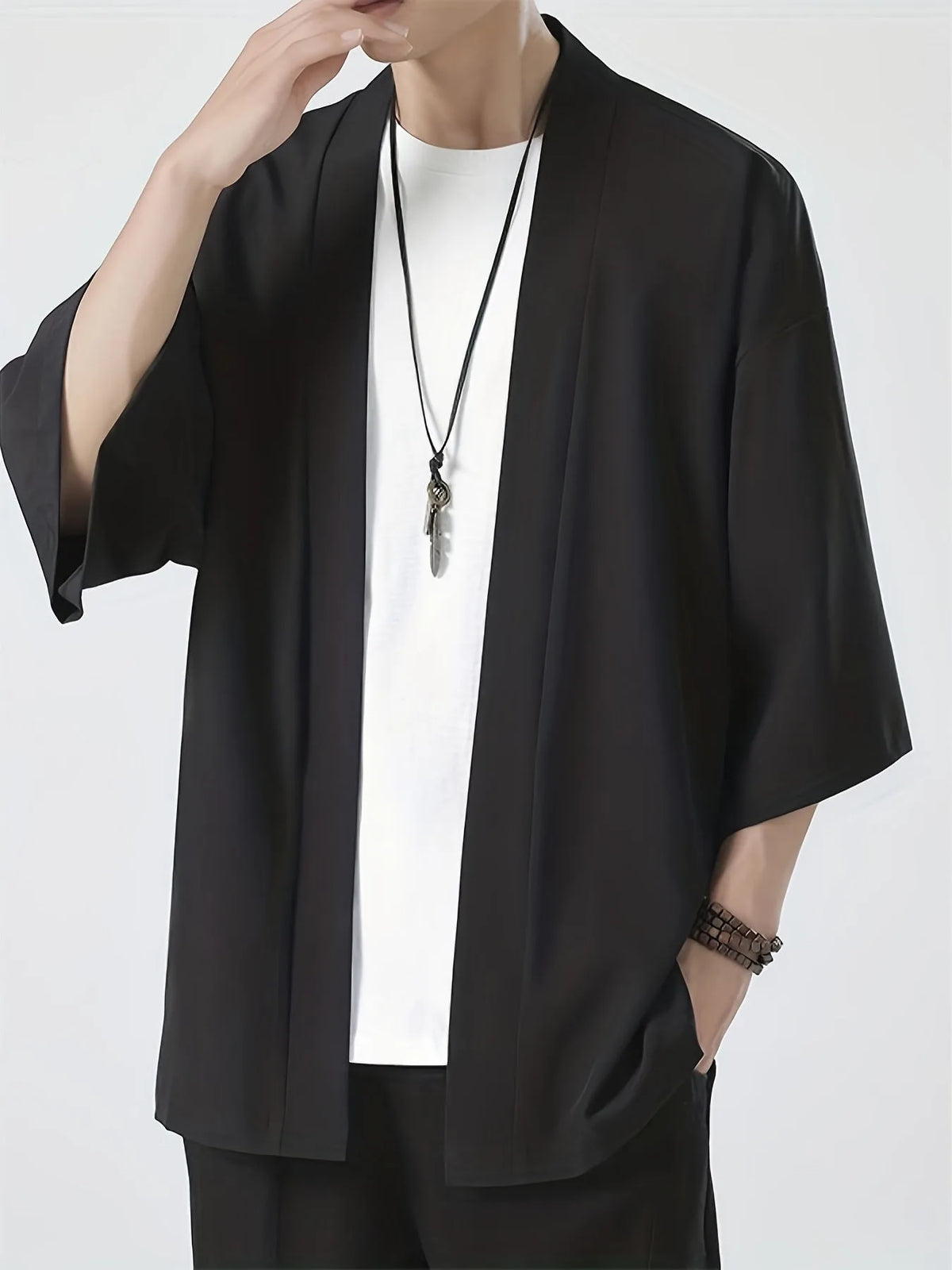 Front view of man wearing an open-front black kimono-style top with wide half sleeves over a white tee