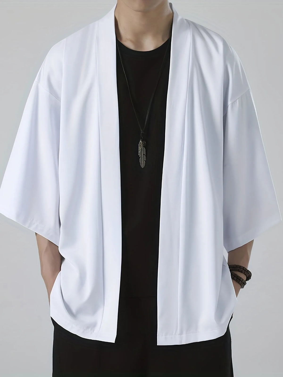 Close-up of a white kimono-style jacket with wide sleeves and open front worn over a black top