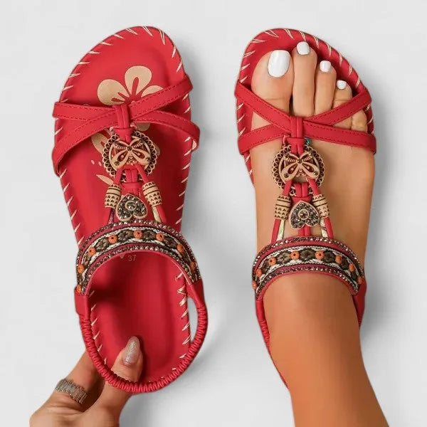 Top view of red beaded boho sandals with woven straps and crossover toe strap, worn on feet