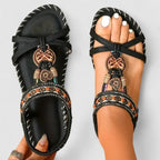 Top view of black woven sandals with beaded ankle strap and tribal charm detail