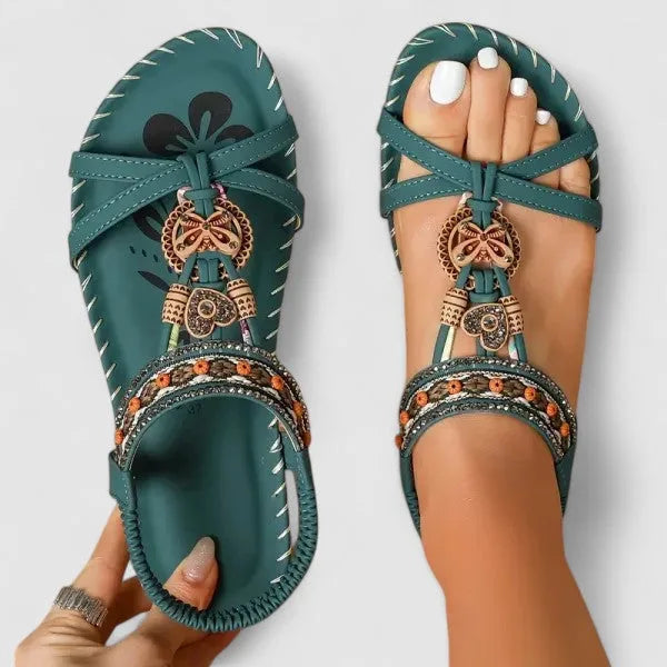Top view of teal sandals featuring crossover straps, beaded trim and floral-print footbed