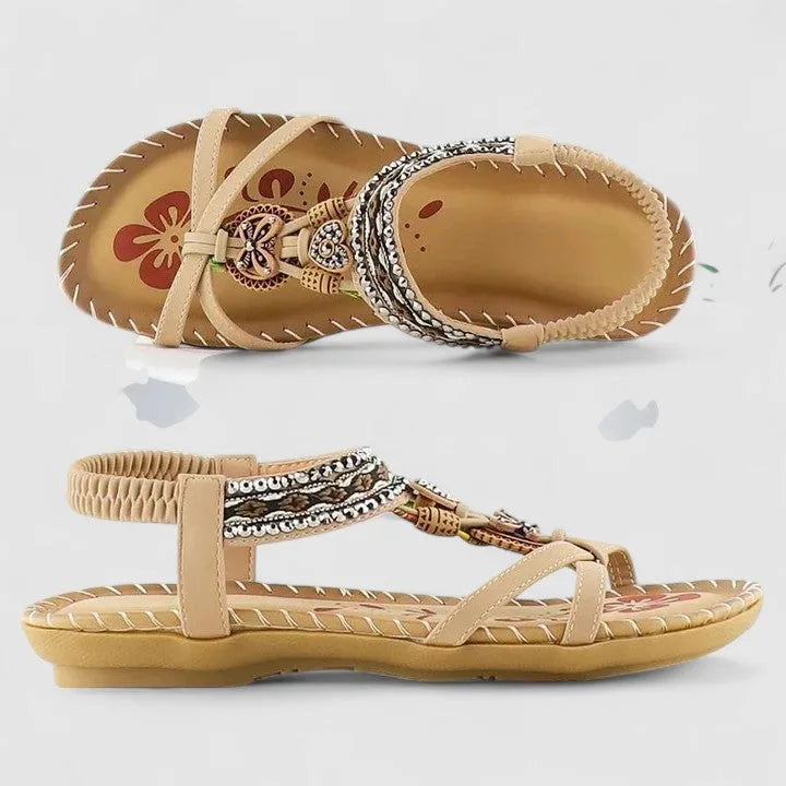 Side and sole profile of beige sandals showing the beaded T-strap design and ribbed tan outsole