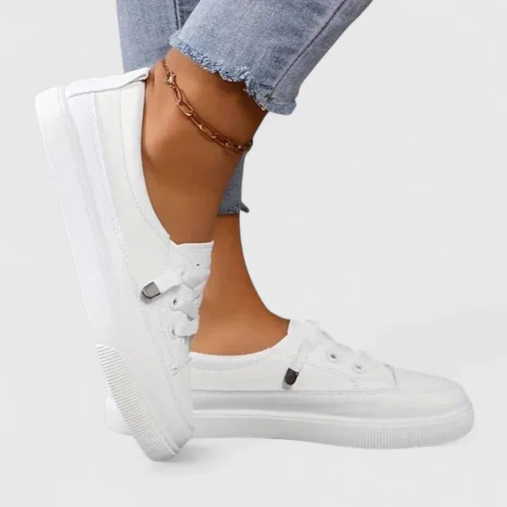 Side view of white lace-up sneaker worn on foot, showing cushioned platform sole and chunky stitched toe cap