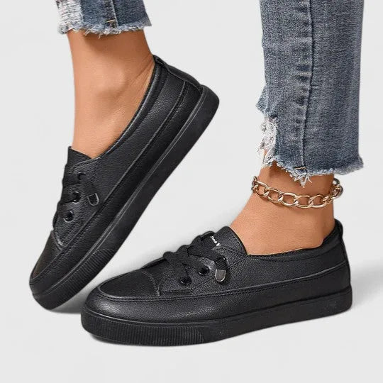 Top view of white sneaker on foot with gold anklet, showing lace eyelets and padded collar