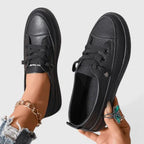 Side angle of white lace-up sneaker on foot, showing stitched panels and sturdy flat platform sole