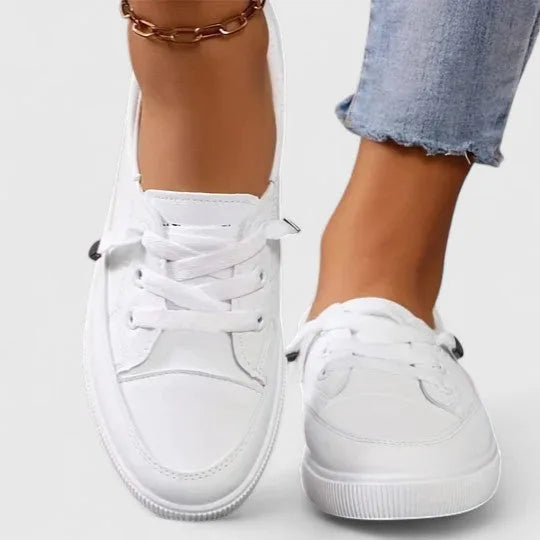 Front angle of white lace-up sneakers on both feet, highlighting round toe shape and thick comfort outsole