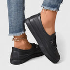 Close-up side view of black lace-up sneaker on foot, showing matte finish and layered sole design