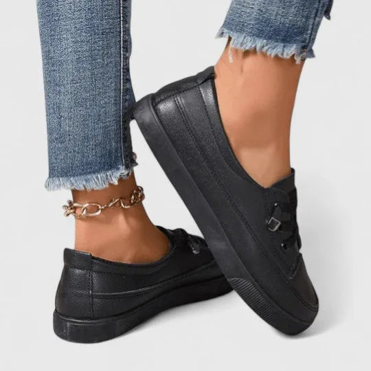 Close-up side view of black lace-up sneaker on foot, showing matte finish and layered sole design