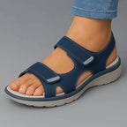 Close-up side view of navy blue strap-adjustable sandal with cushioned sole worn with rolled denim jeans