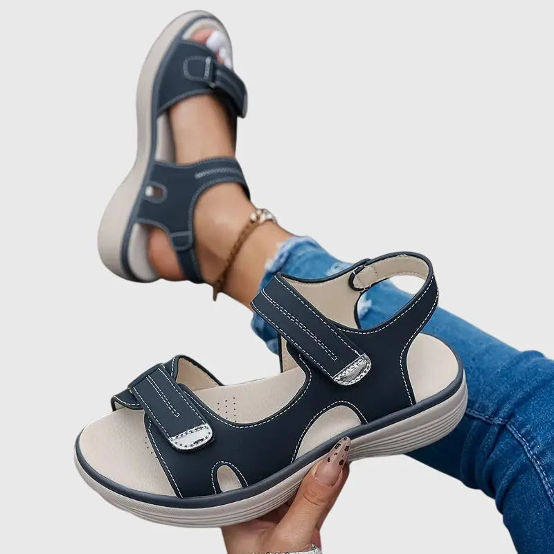 Close-up top view of black sandal showing perforated footbed texture and touch-strap buckle