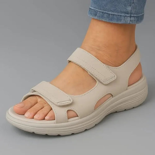 Side profile of beige adjustable strap sandal showing cut-out detailing and thick comfort sole