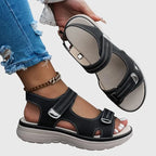 Pair of black touch-strap sandals shown from above and side, cut-out design with cushioned beige footbed