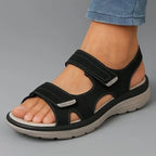 Angled view of black touch-fasten strap sandal with contrast stitching and chunky grip sole