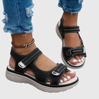 Front angle of black sandals worn on foot showing open toe and dual touch-strap closures