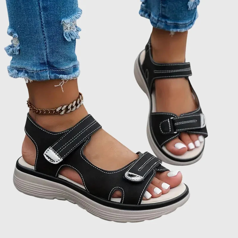 Front angle of black sandals worn on foot showing open toe and dual touch-strap closures