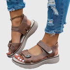 Both black sandals shown together, one worn and one held, revealing chunky platform sole underside