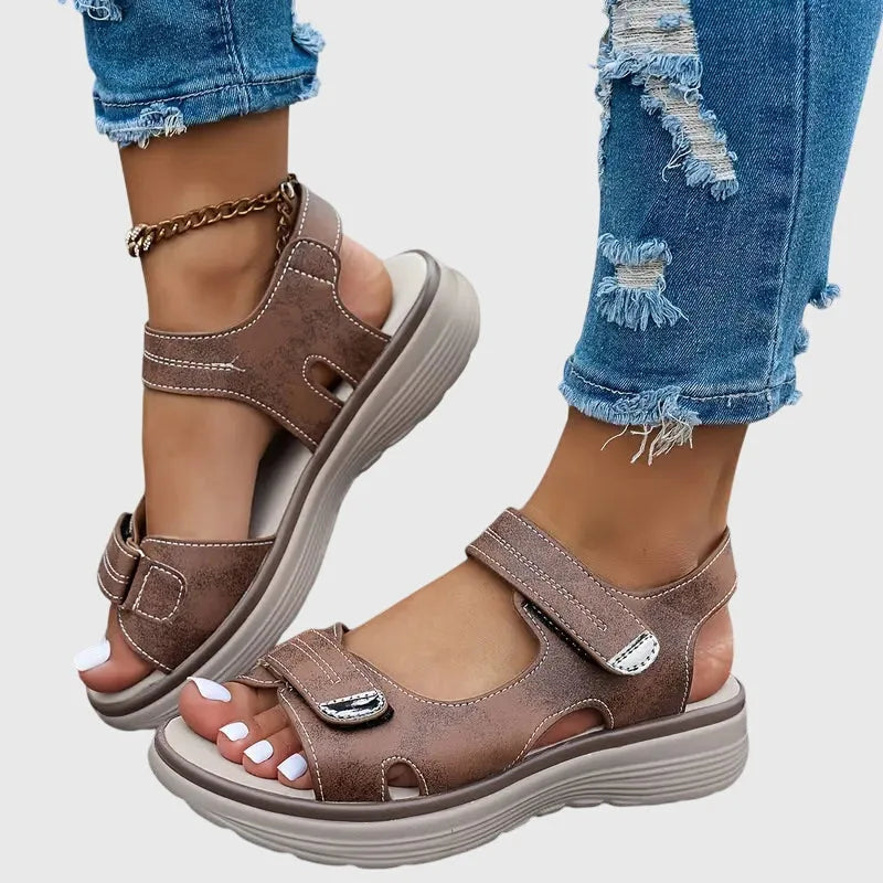 Both black sandals shown together, one worn and one held, revealing chunky platform sole underside