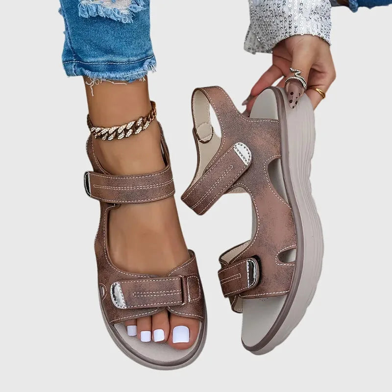Pair of brown touch-strap sandals from above, showing cut-out panels and cushioned beige footbed