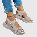 Beige sandal worn on foot, side angle showing single touch-strap closure and thick comfort sole