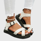 Angled view of an off-white crisscross sandal with adjustable ankle buckle and thick cushioned platform sole