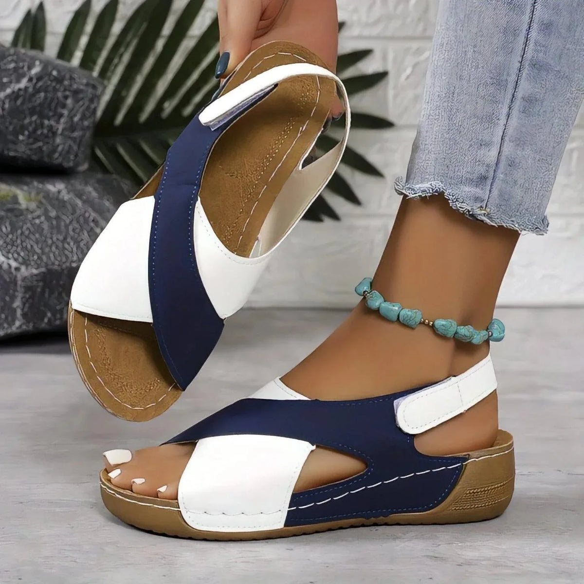 Close-up of navy and green crisscross wedge sandals worn on both feet, back view