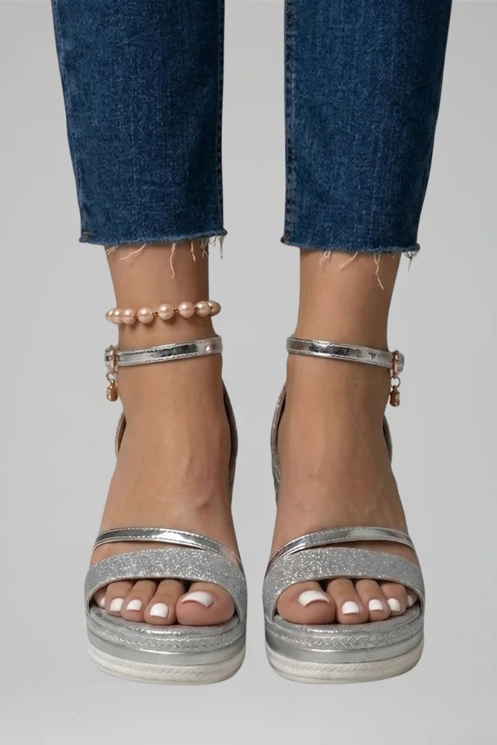 Front close-up of feet in silver metallic wedge sandals with glitter strap and pearl anklet accessory