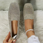 Close-up top view of beige knit loafers with woven mesh toe detail, held by hand showing tan insole
