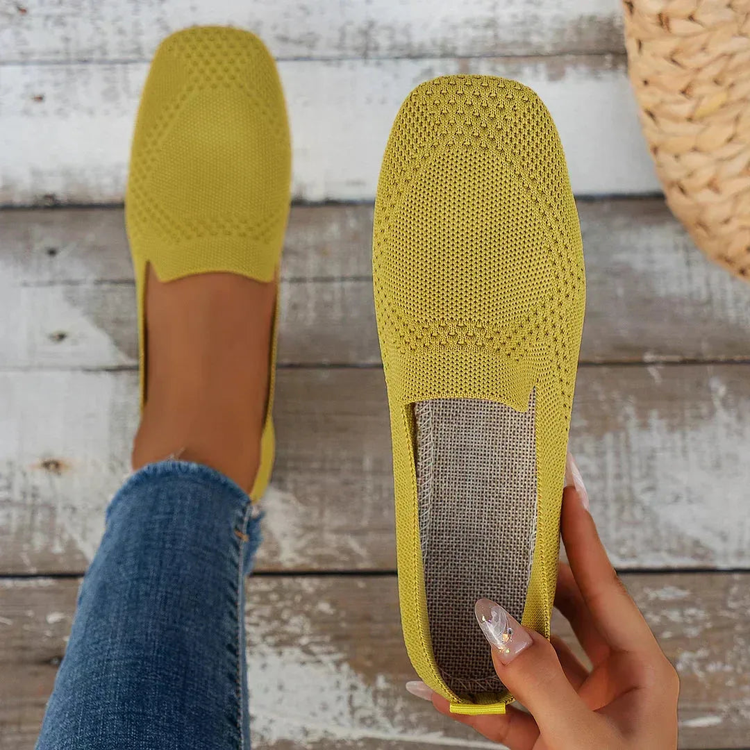 Mustard yellow knit loafer sole view showing woven insole texture, held in hand on wooden planks