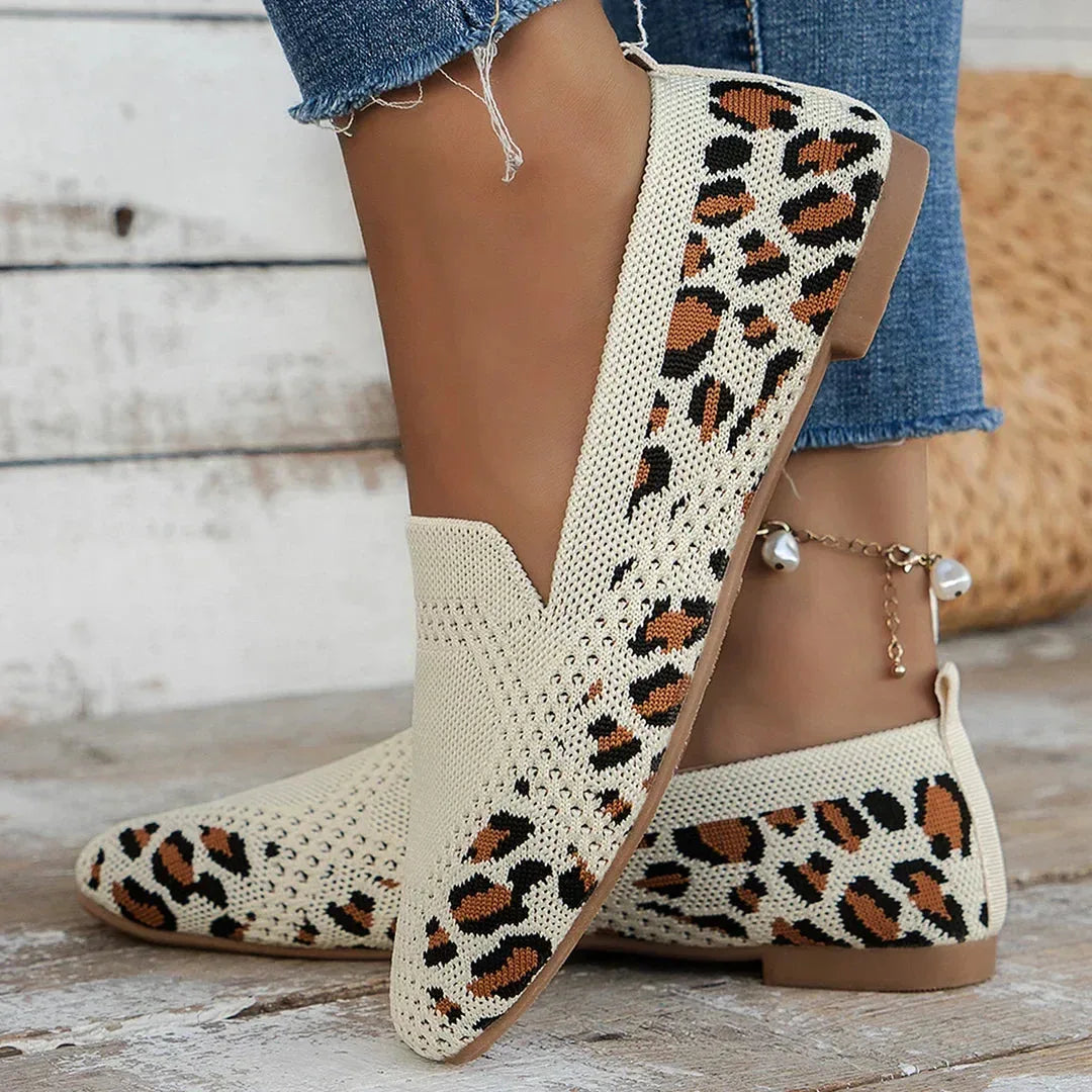 Cream knit loafers with leopard print trim, shown from behind near wooden steps and denim hem