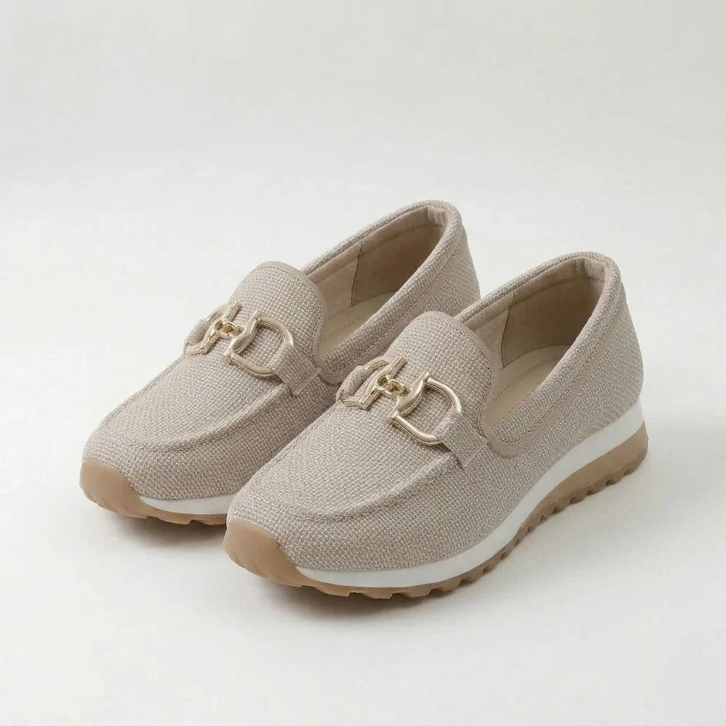 Front angled view of a pair of beige knit loafer sneakers with a gold horsebit buckle and white midsole