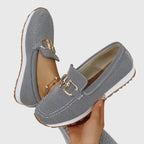 Close-up of a grey knit loafer's gold horsebit hardware and chunky tan tread sole