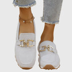 Light grey knit slip-on loafer with gold buckle detail worn on a model's foot next to jeans