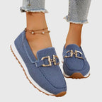 Close-up front view of a white knit slip-on loafer with gold horsebit trim on a model's foot