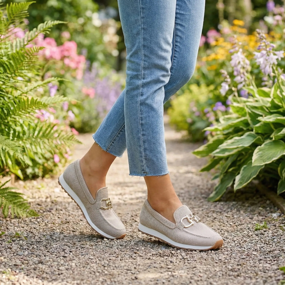 Grey knit slip-on loafer with gold horsebit trim worn on foot, side front view