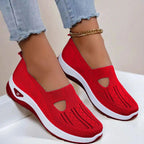 Side view of red knit slip-on shoes with cut-out vamp detail and white platform sole, worn with rolled denim jeans