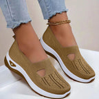 Side view of coffee brown knit slip-on shoes with cut-out detail and white chunky sole, shown on feet with cuffed jeans