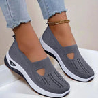 Side view of dark grey knit slip-on shoes with cut-out detail and white platform sole, styled with light denim jeans