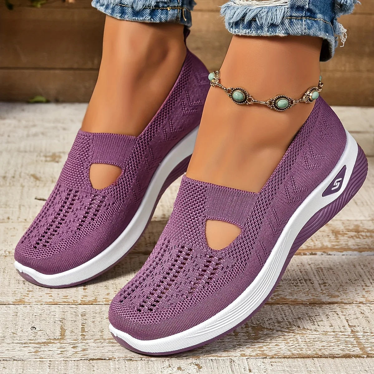 Close-up side view of purple knit slip-on shoe with cut-out detail and white chunky sole, worn with ripped jeans and a turquoise anklet