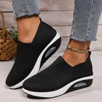 Side view of black knit slip-on sneaker worn on foot, showing V-cut collar and chunky white midsole