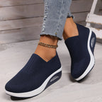 Navy blue knit slip-on sneaker worn with cropped jeans, showing white platform wedge sole