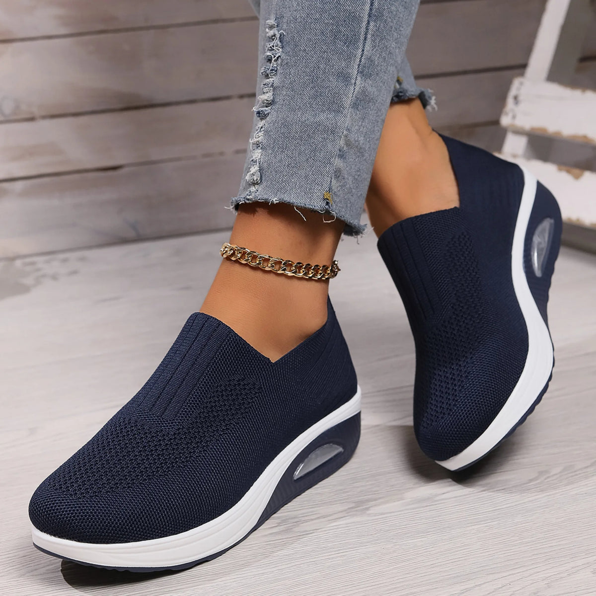 Navy blue knit slip-on sneaker worn with cropped jeans, showing white platform wedge sole