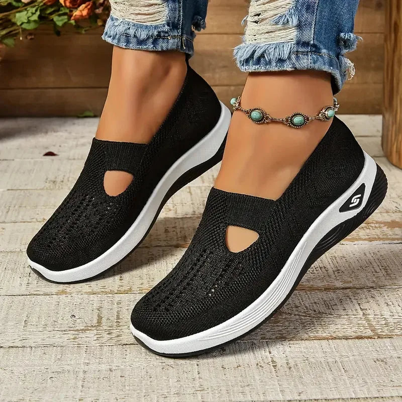 Front-on shot of black knit slip-on sneakers with teardrop cut-out, white platform midsole and black ribbed outsole