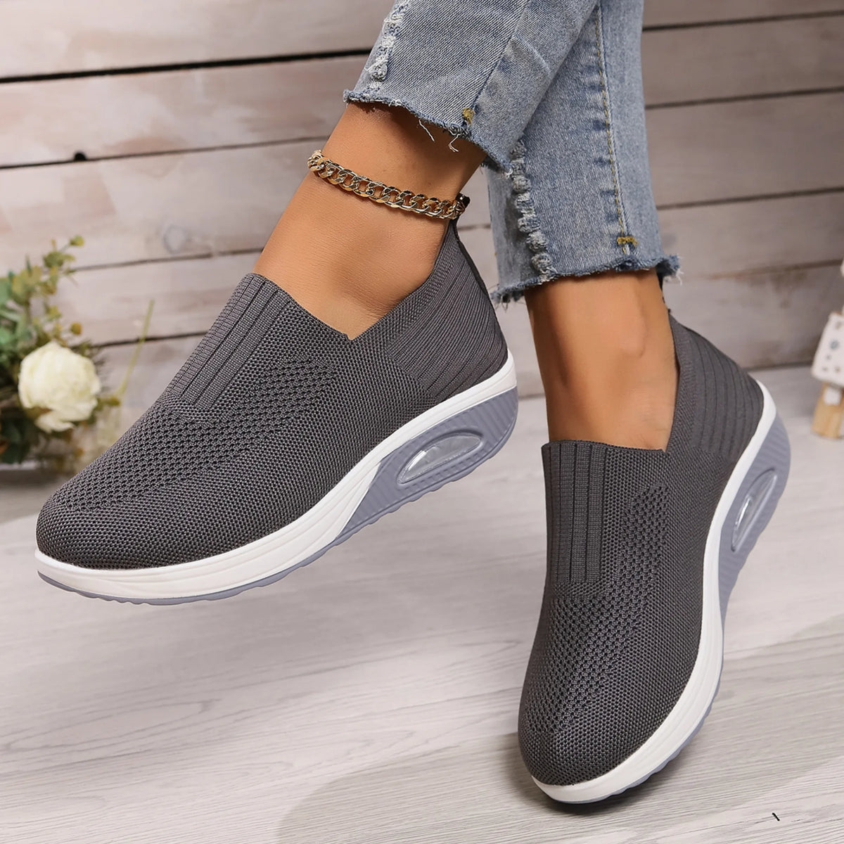 Grey knit slip-on sneaker worn mid-step, showing V-cut vamp and two-tone grey sole