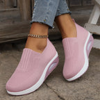 Pink knit slip-on sneakers worn on feet, angled view showing breathable mesh texture and platform sole