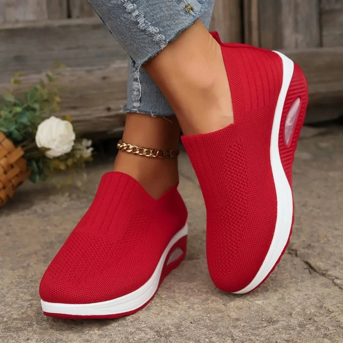 Red knit slip-on sneaker worn with rolled denim, showing air-cushion heel pod and white platform base