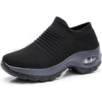 Side angle of a black knitted sneaker showing the ribbed ankle cuff and grey chunky sole with air bubble