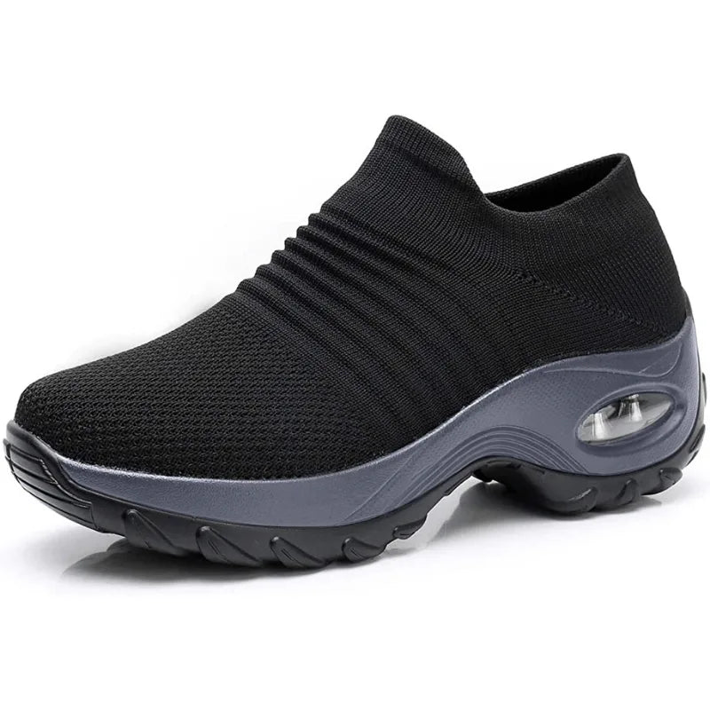 Side angle of a black knitted sneaker showing the ribbed ankle cuff and grey chunky sole with air bubble