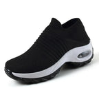 Angled front view of an all-black knit sneaker with ribbed collar and textured black sole