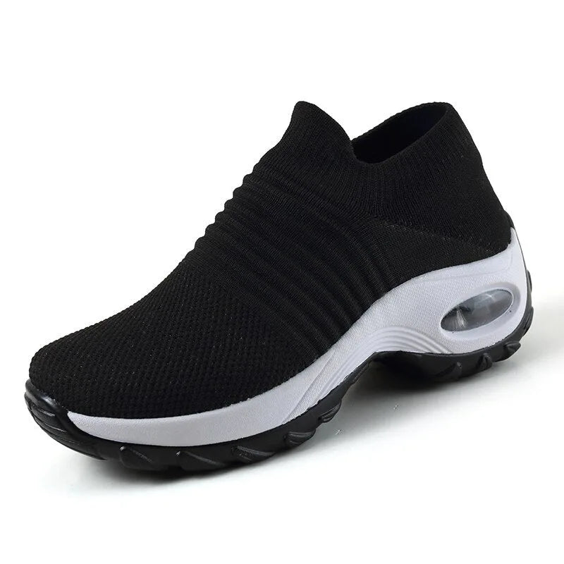 Angled front view of an all-black knit sneaker with ribbed collar and textured black sole