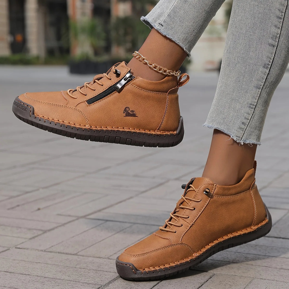 Angled view of tan ankle boots showing the zip pull, lace eyelets and ram logo on the side panel